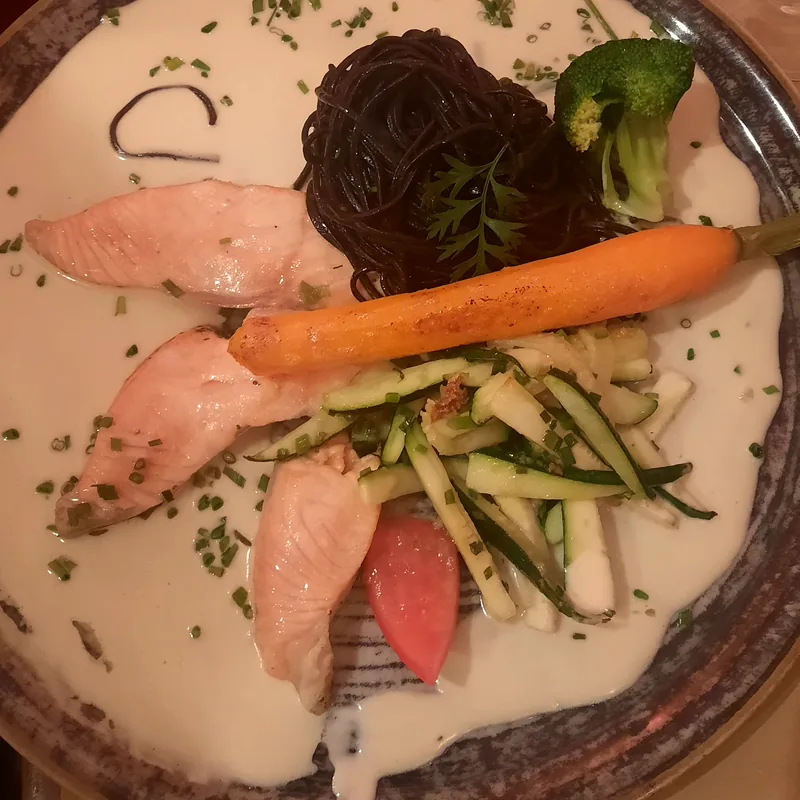 Assiette de poisson avec pâtes noires, carotte glacée et courgettes